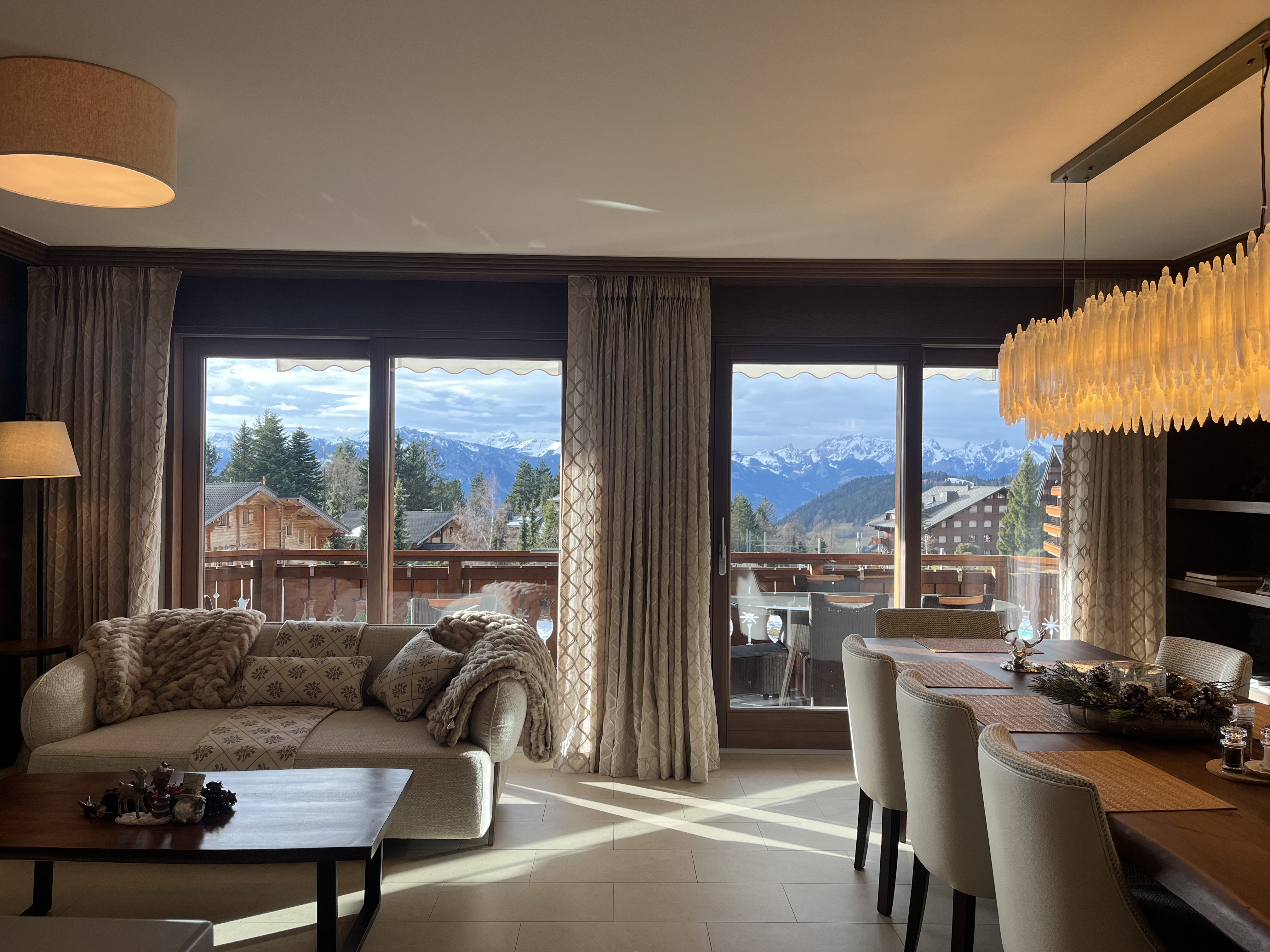 Photo of the large, luxurious living room with mountain views, featuring sofas, armchairs, and artwork, located in the Chalet RoyAlp hotel in Villars-sur-Ollon.