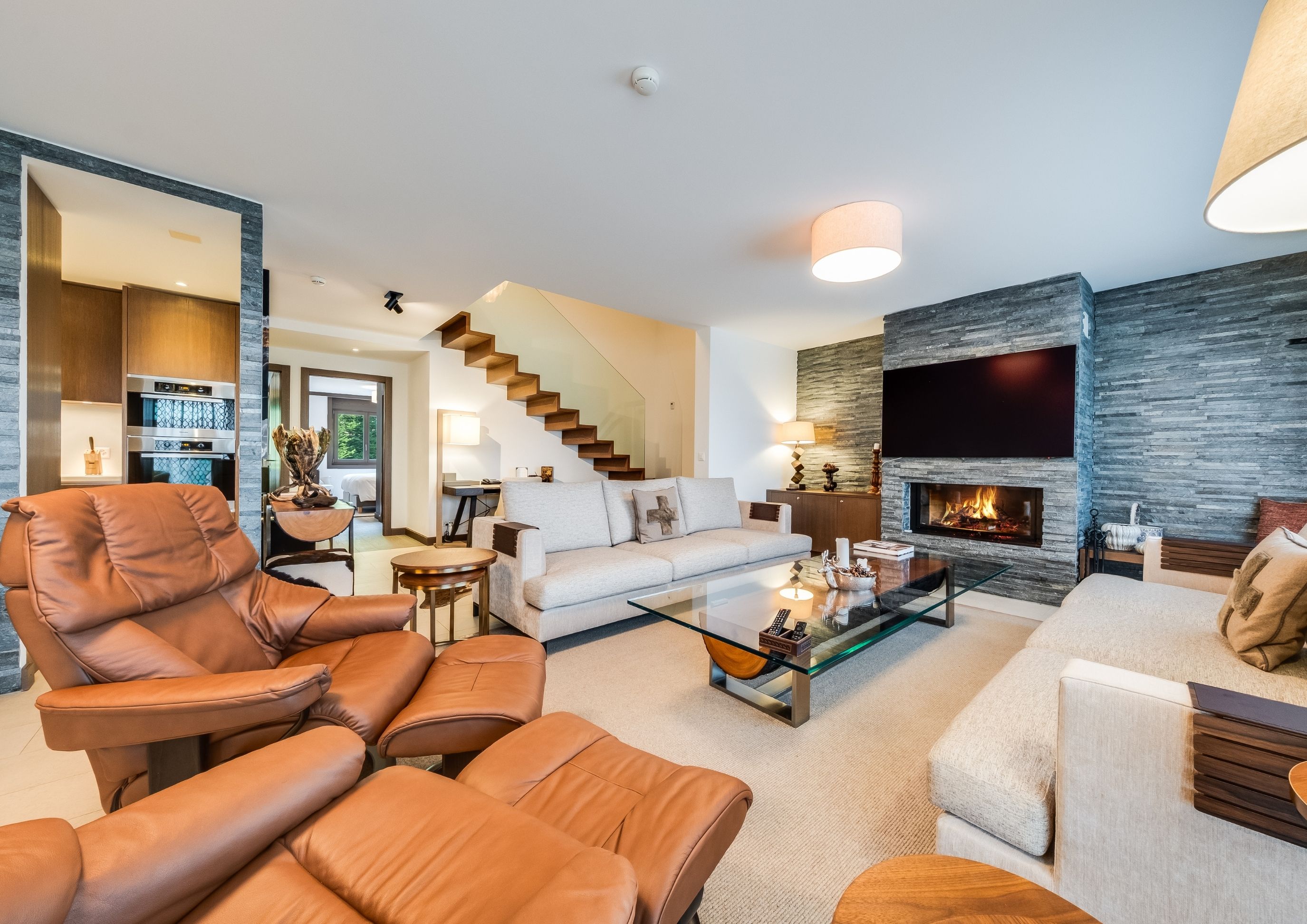 Photo of the large, luxurious living room with mountain views, featuring sofas, armchairs, and artwork, located in the Chalet RoyAlp hotel in Villars-sur-Ollon.