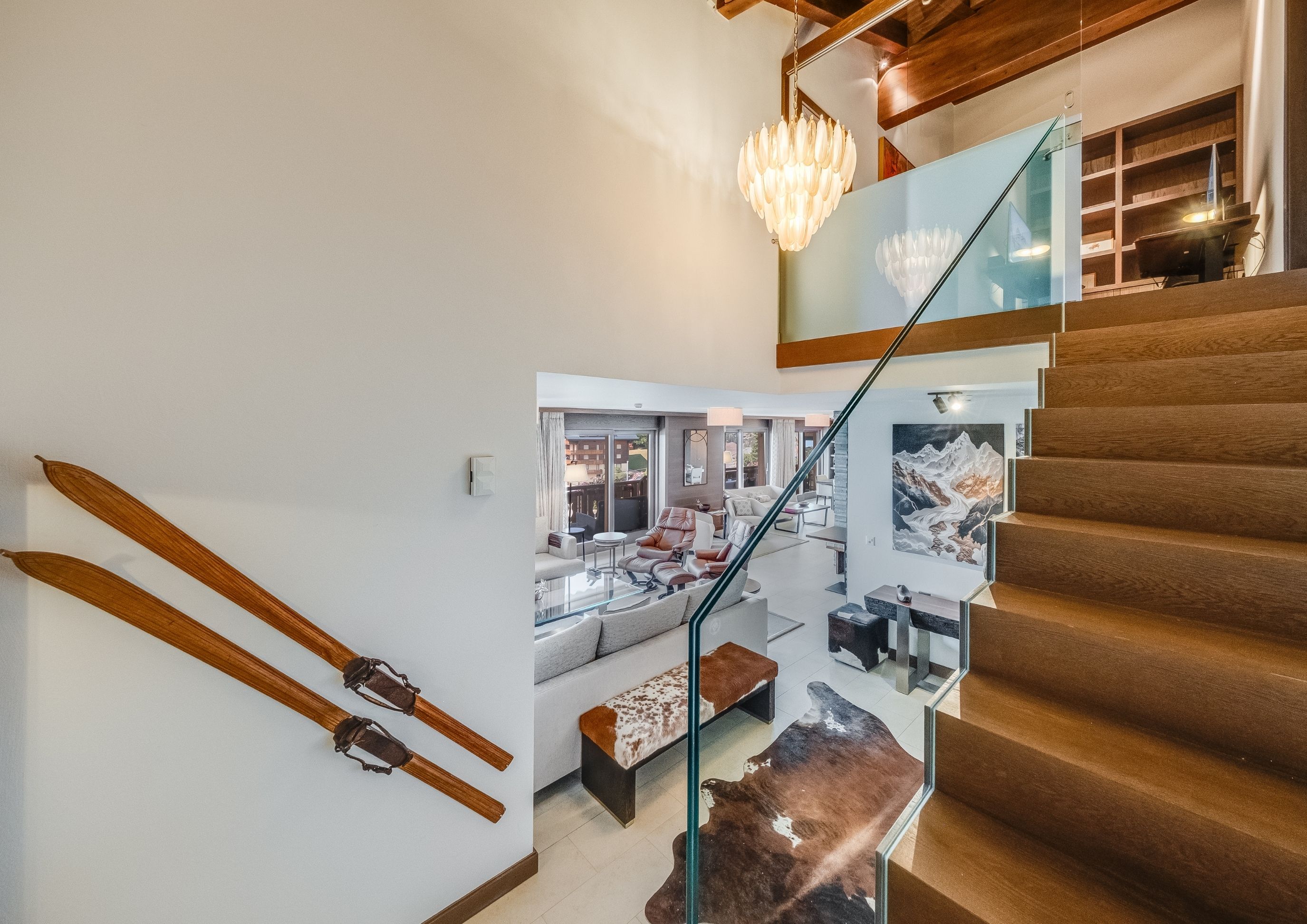 Photo of the living room in the Chalet Royalp duplex family residence, a cozy space with armchairs, a staircase, an office area, and a view of the kitchen entrance.