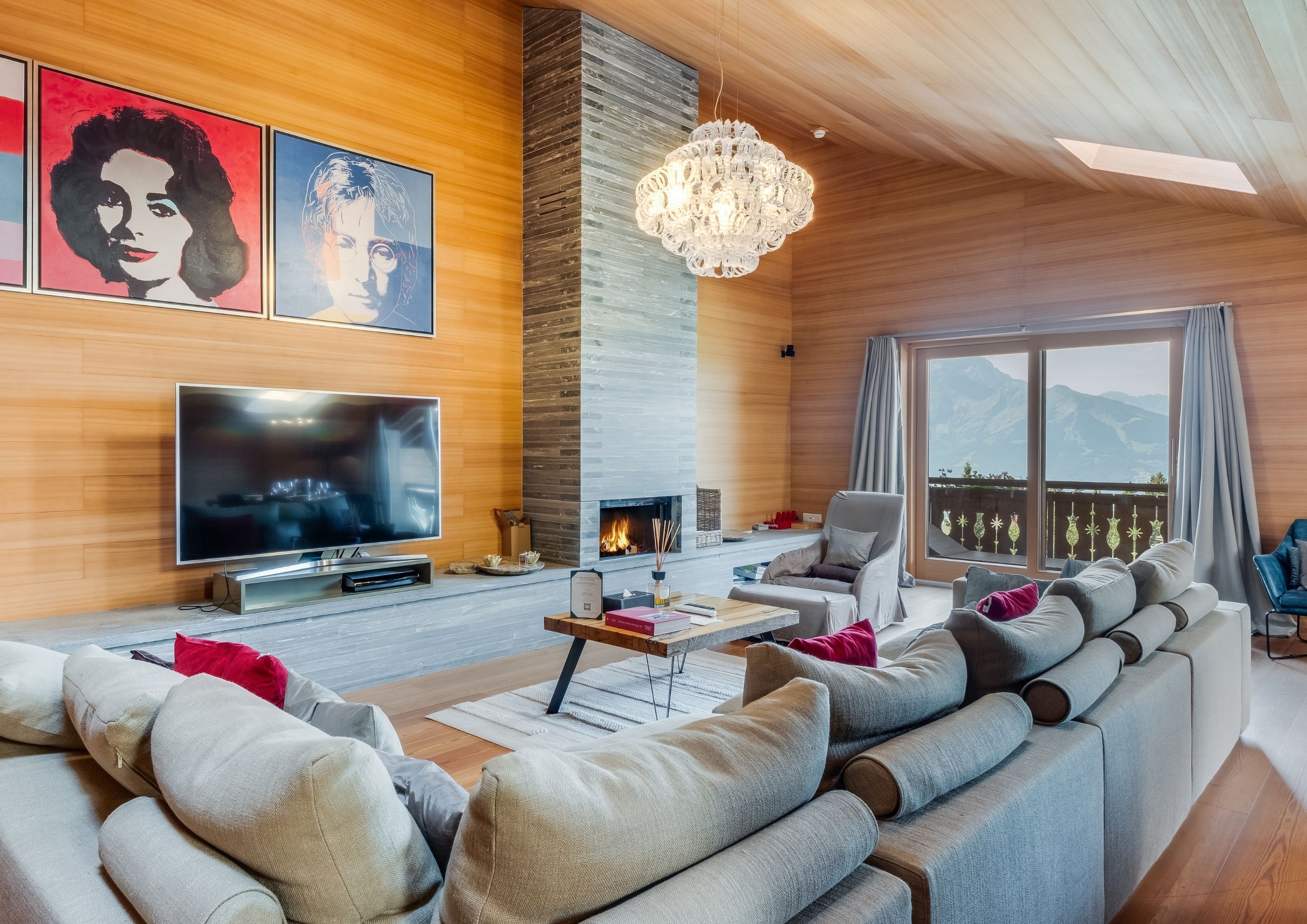 Photo of the living room with large sofa, TV and fireplace in the modern penthouse at the Chalet RoyAlp hotel in Villars.