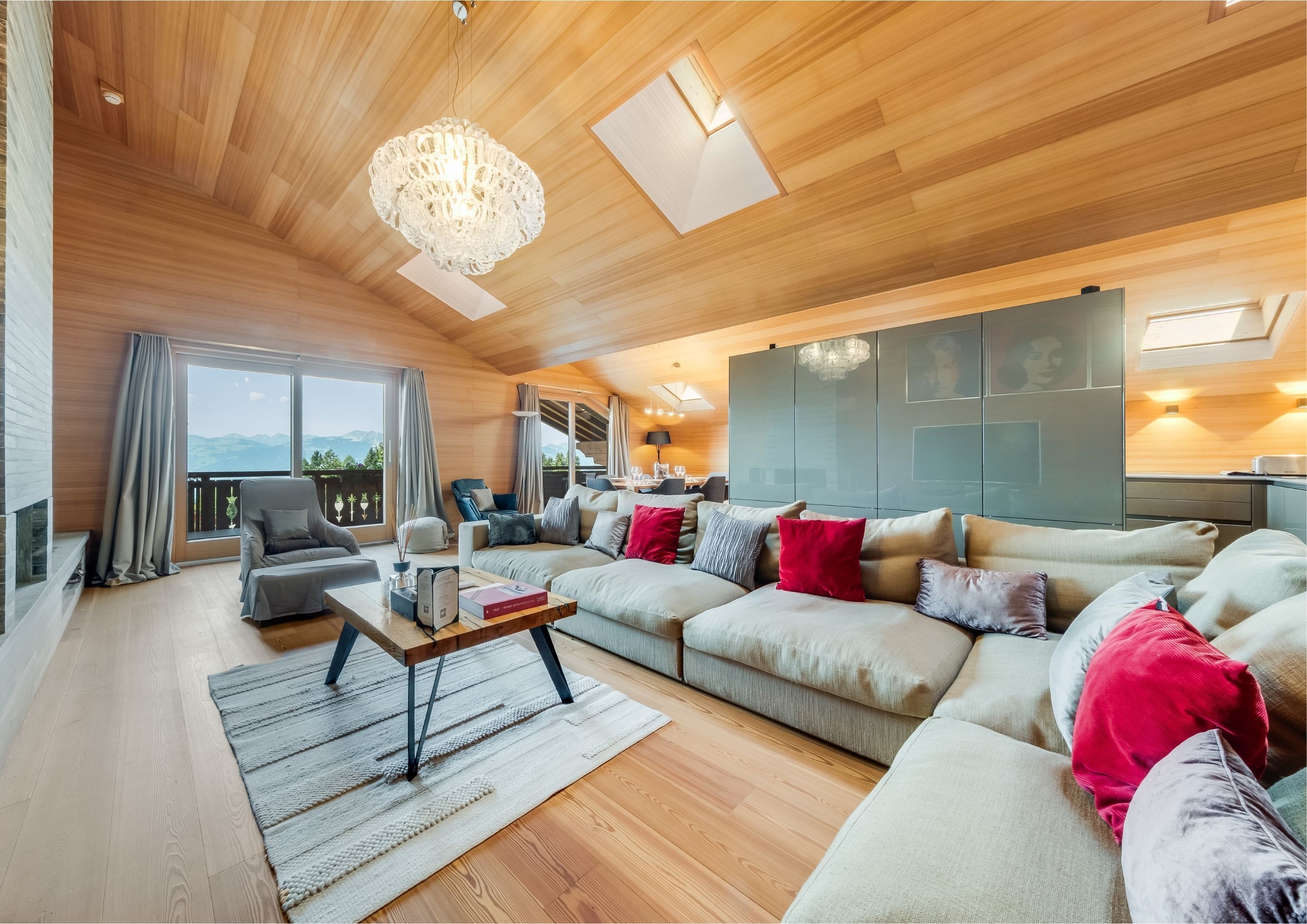 Photo of the living room with large sofa, TV and fireplace in the modern penthouse at the Chalet RoyAlp hotel in Villars.