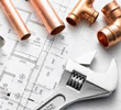 Adjustable wrench and copper plumbing pipes on a detailed construction blueprint.