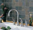 Modern kitchen sink with silver faucet and handles against tiled backsplash with decor items.