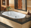 White built-in bathtub with dark marble surround and flowers on edge in a modern bathroom.