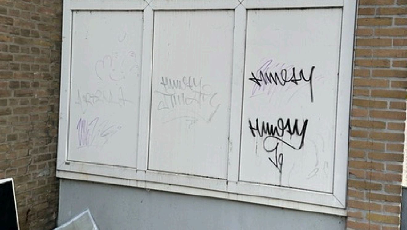 Witte trespa gevelpanelen bij een VvE in Rotterdam met zwarte en paarse graffiti-tags, vóór de verwijdering door Mattanna B.V.