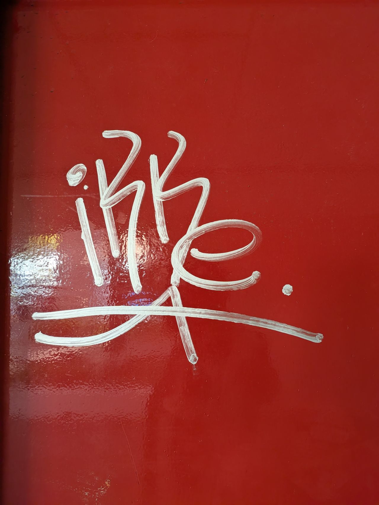 Witte lakstift-graffiti op een rood gecoate deur bij een VvE in Vlaardingen, vóór de verwijdering door Mattanna B.V.