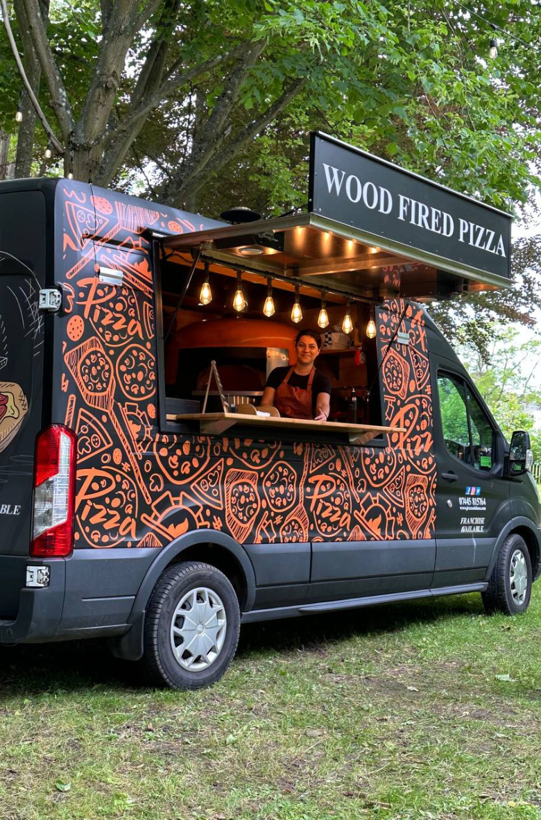 Foosball table with red and blue players in front of an orange sofa with cushions in a cozy room.