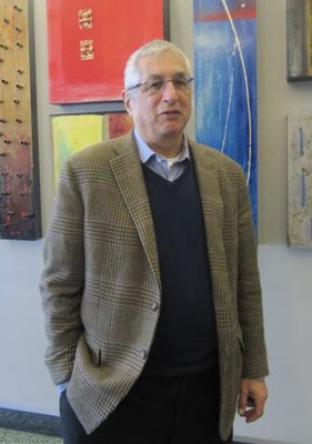 Photo of man standing in front of several pieces of abstract art