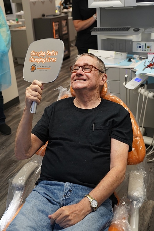 Smiling dental patient checking out his completed work