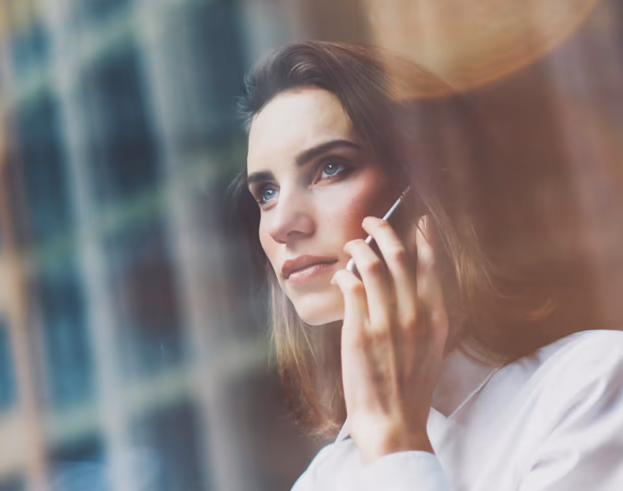 Woman smiling thoughtfully while talking on the phone