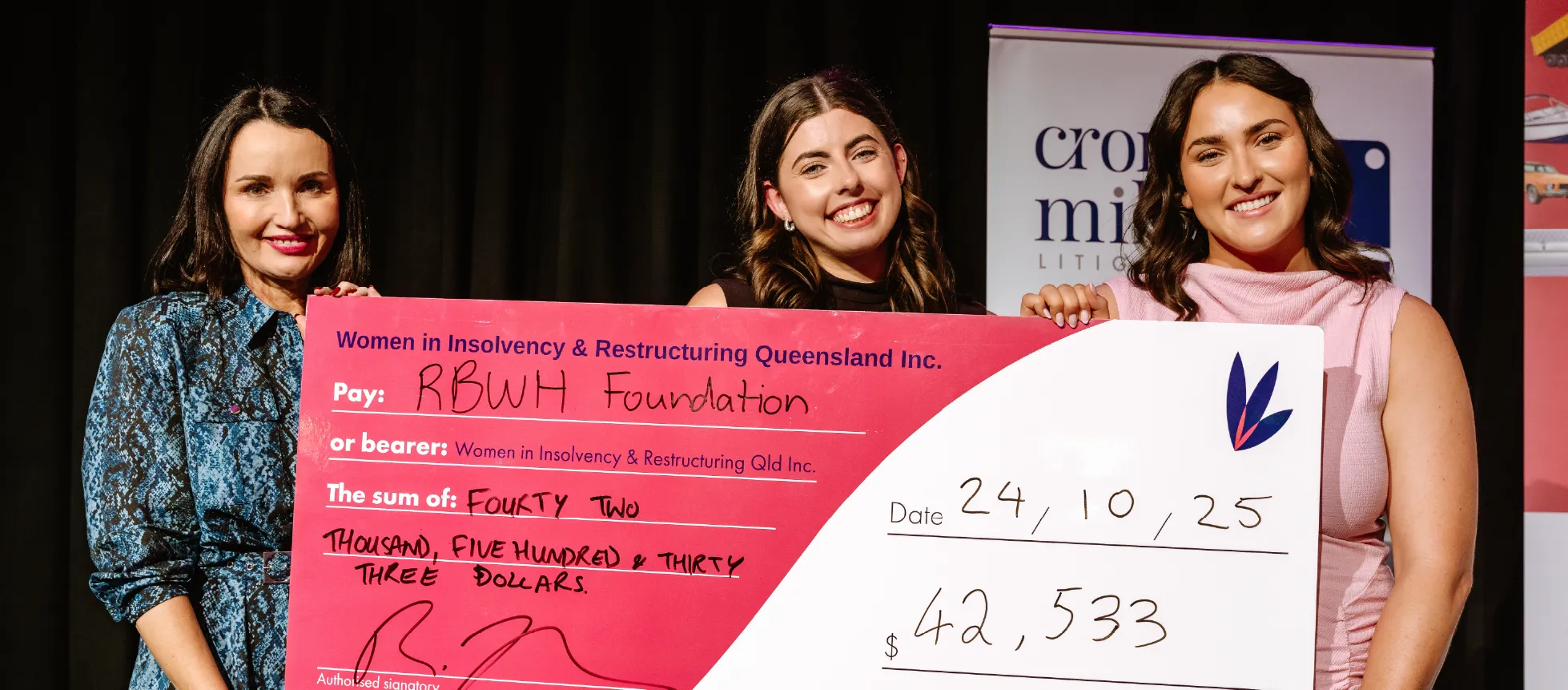 Three WIRQ members holding an oversized charity cheque made out to the RBWH Foundation at a fundraising event.