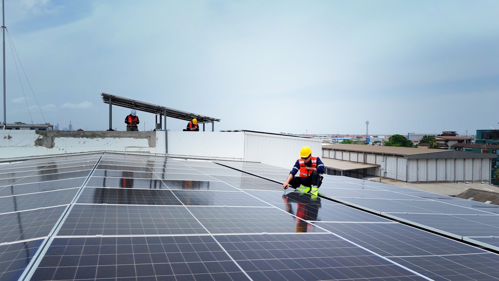 Engineer on warehouse rooftop inspecting solar panels