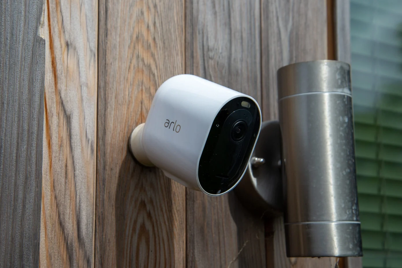 Arlo Essential Spotlight Camera – övervakningskamera monterad på en trävägg
