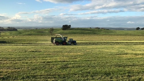 harvester and tractor picking up grass