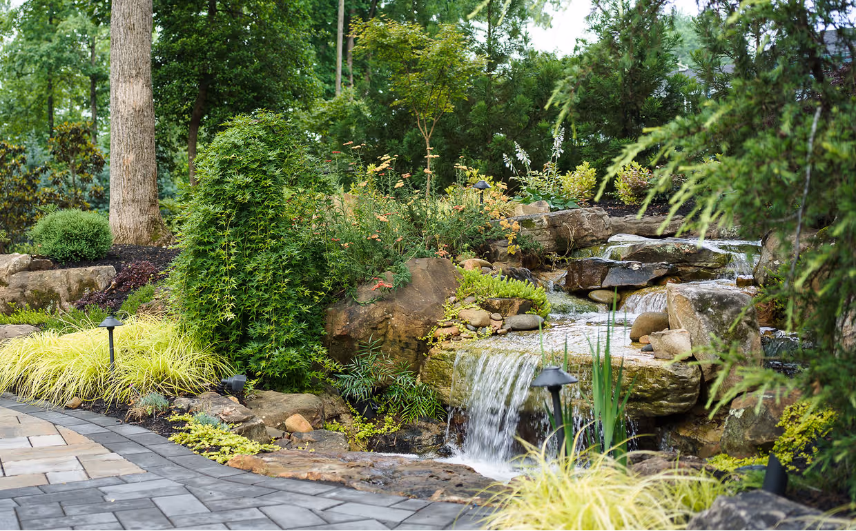 A custom-built backyard waterfall with natural stone and surrounding plants