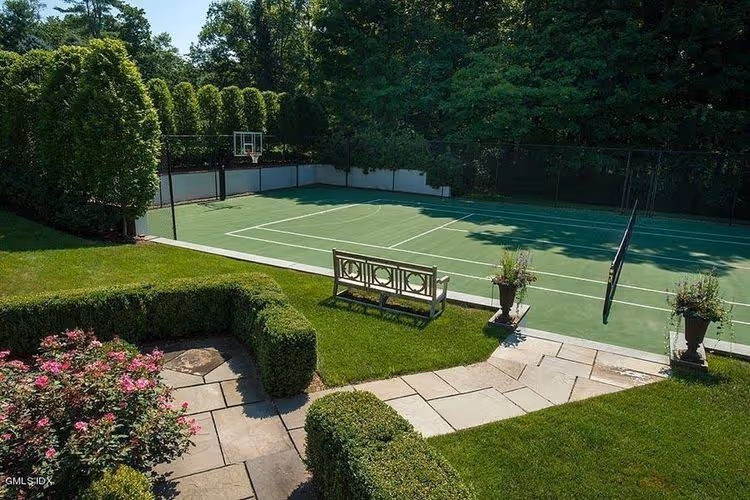 Custom Asheville backyard sports court surrounded by trees, featuring a professional surface with netting and fencing.