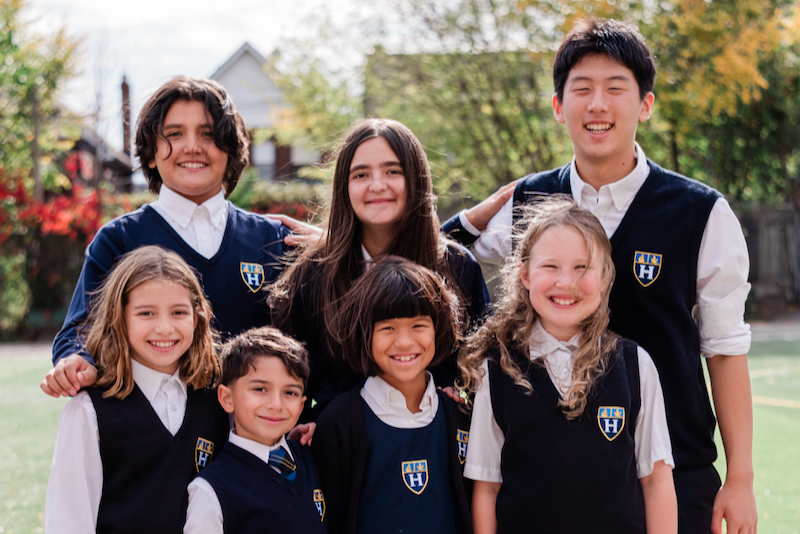 Three high school students in green school shirts and jeans, smiling and cheering.