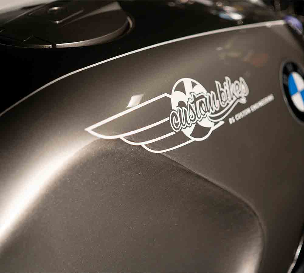 BMW K100 Gas Tank The original gas tank has a great shape to it and the angle of its mount has as an aggressive look and feeling of speed, even when stationery. However, when the original Tupperware is removed it reveals that ugly cut away at the bottom of the tank. In all the custom builds I have seen this part seems to get forgotten about and has not been addressed leaving it looking unfinished and if there is something missing. As I wanted to use the original tank a solution had to be found, so I moulded carbon fibre panels that clip in place hiding that empty void., a much better solution.