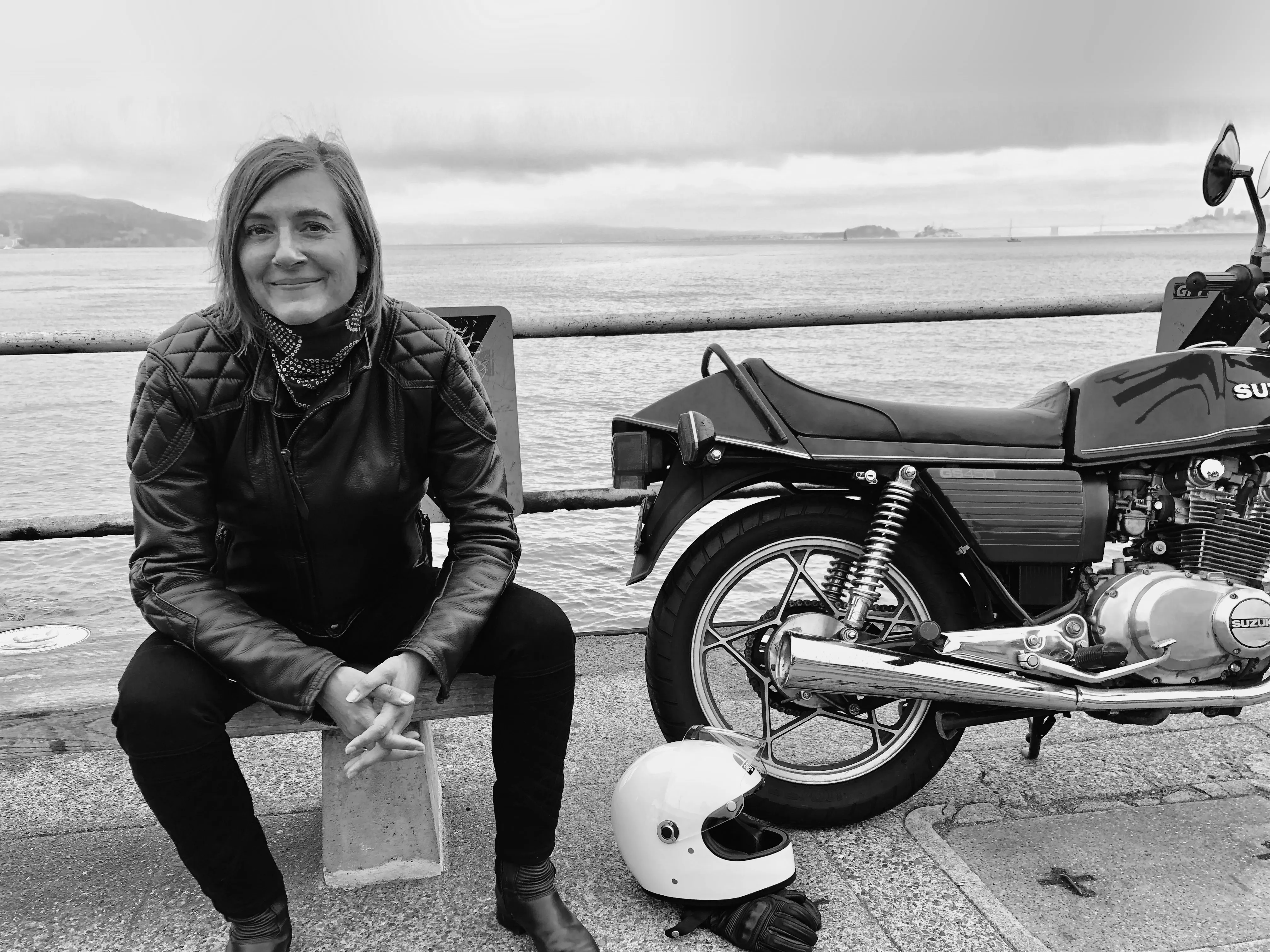 Portrait of Maîa Cybelle Carpenter sitting next to her Suzuki Motorcycle in front of the golden gate bridge San Francisco.
