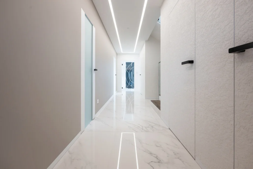 Tall Dorsis Fortius frameless doors in microcement finish for a concrete wall appearance.