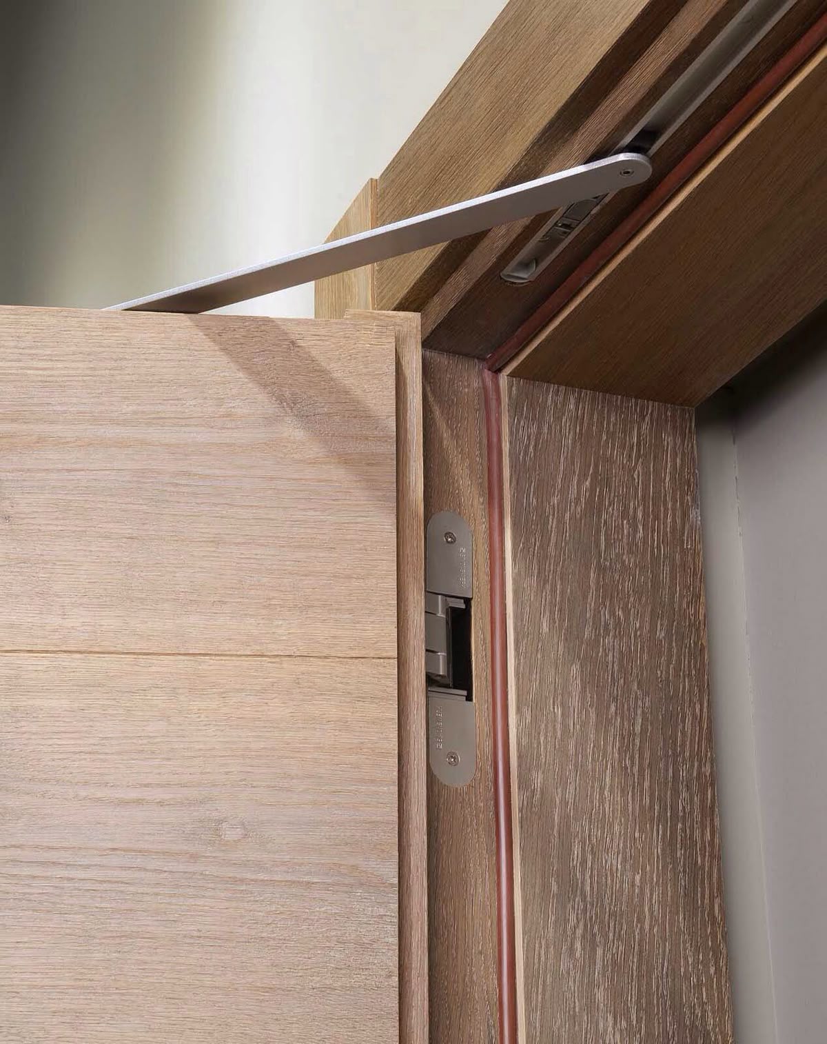 Assa Abloy concealed door closer on an outswing wood veneer door with Simonswerk Tectus silver concealed hinges.
