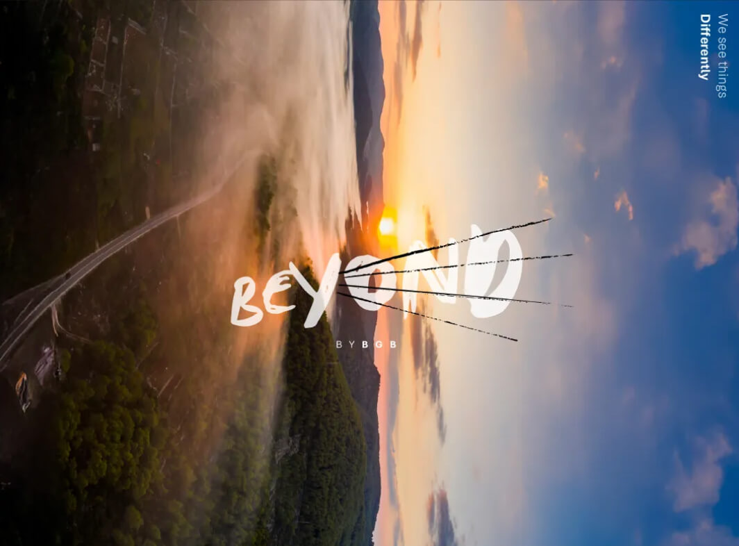 Sunrise over a misty forested landscape with a road winding through it, text reads 'BEYOND BY BGB' and 'We see things Differently' in the sky.