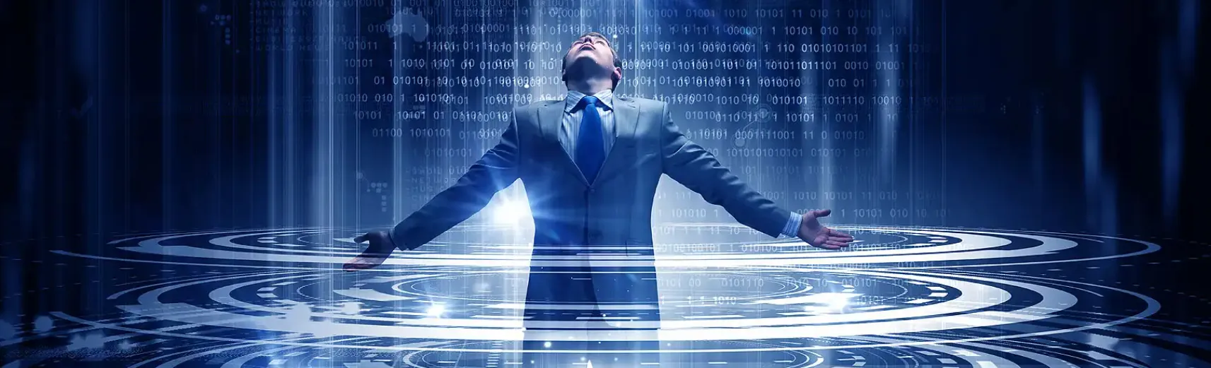 Un homme en costume se tient debout, les bras tendus et la tête penchée vers le haut, au milieu d'un environnement numérique de haute technologie. Autour de lui, des motifs circulaires illuminés et un code binaire créent une atmosphère futuriste et immersive.