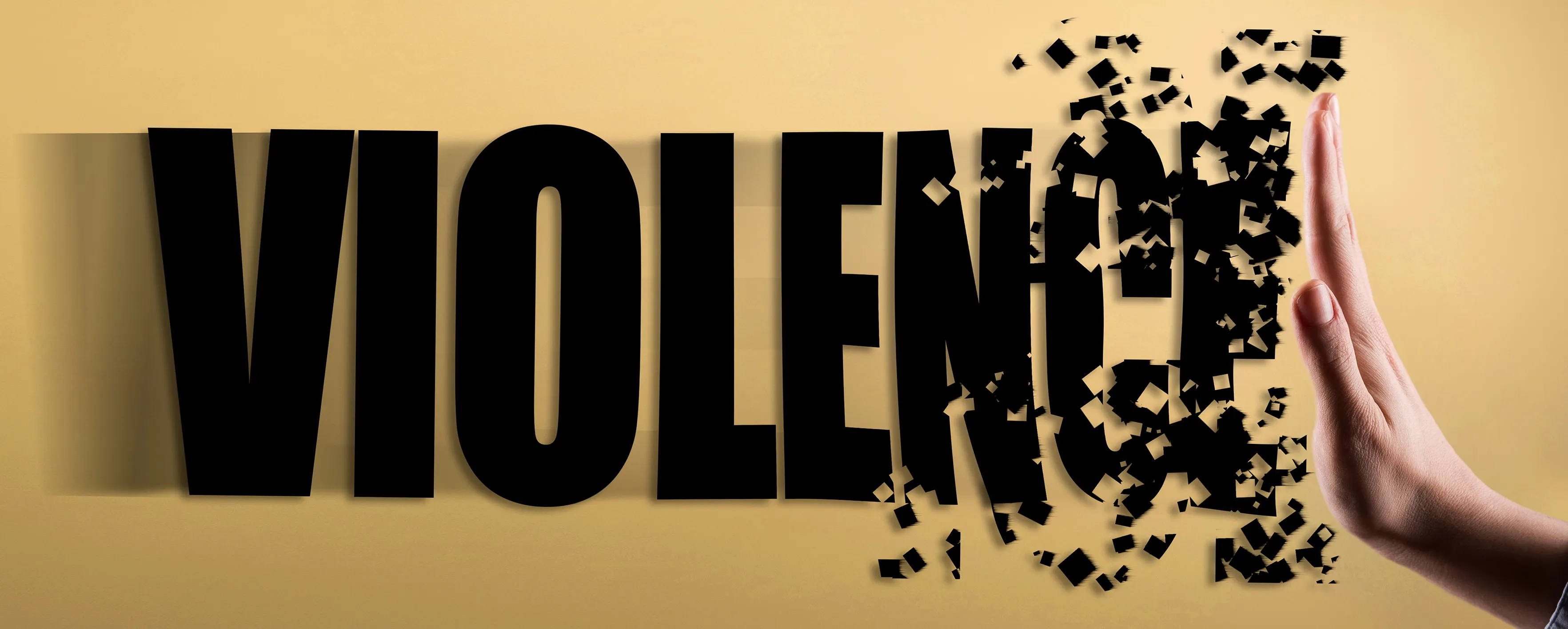 Le mot VIOLENCE en lettres noires grasses sur fond beige, les dernières lettres se désintégrant en petits morceaux lorsqu'une main les pousse.