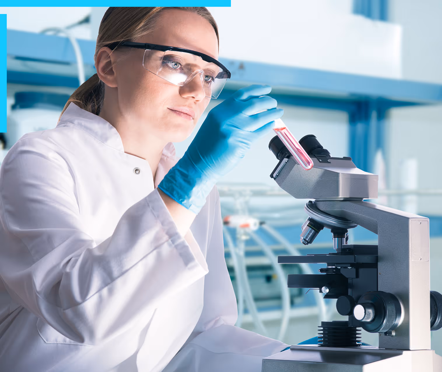 A female scientist holding up a test tube in front of the microscope in a research laboratory
