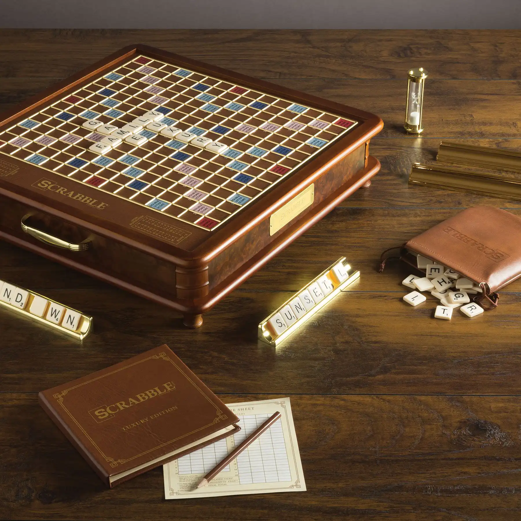 Close-up of a high-end, luxury Scrabble game set featuring a polished wooden cabinet, gold-plated tile racks, leather storage pouch, and scorebook.