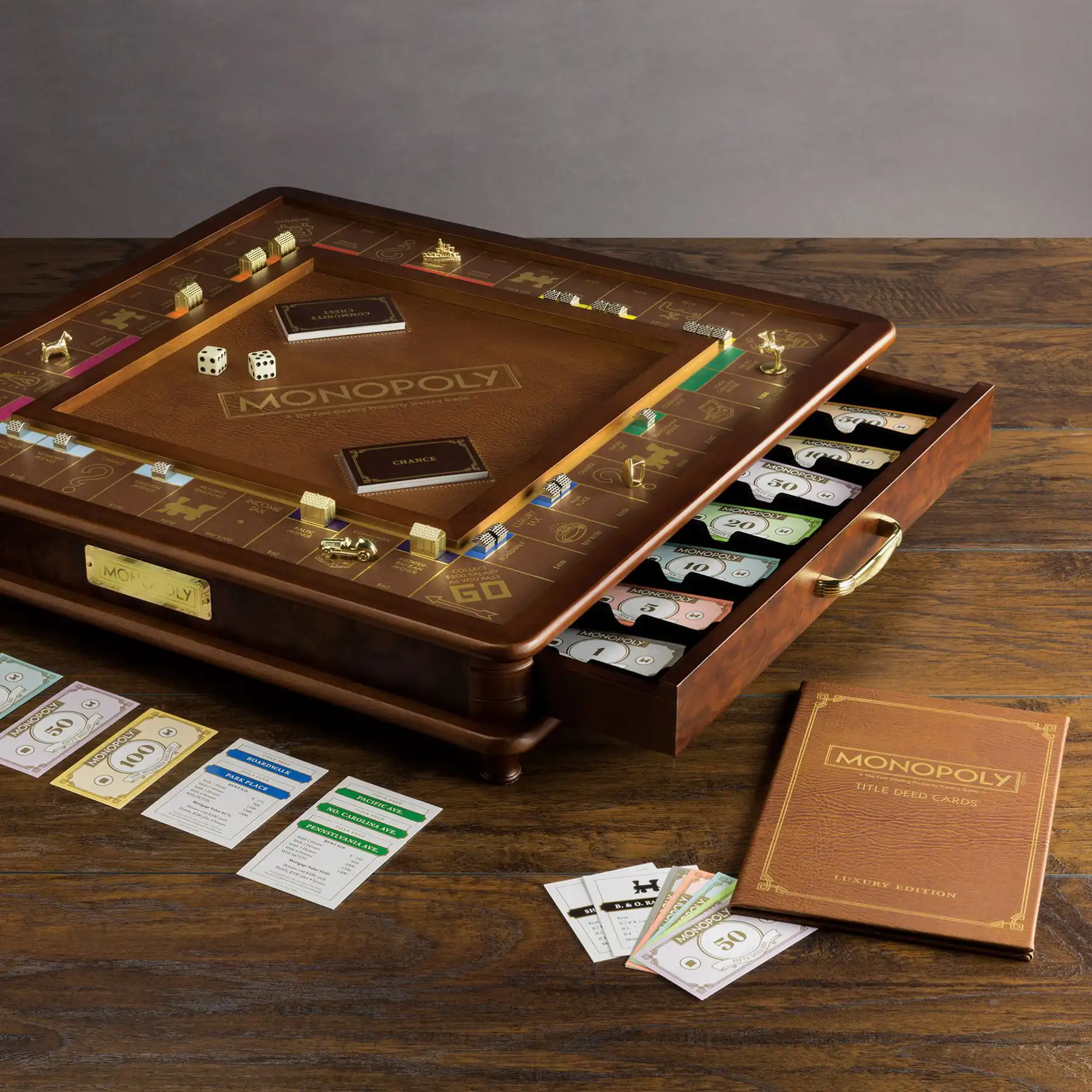 Elevated luxury Monopoly set with a wooden cabinet, rich leather game board, gold-toned playing pieces, and a drawer for money and deeds.