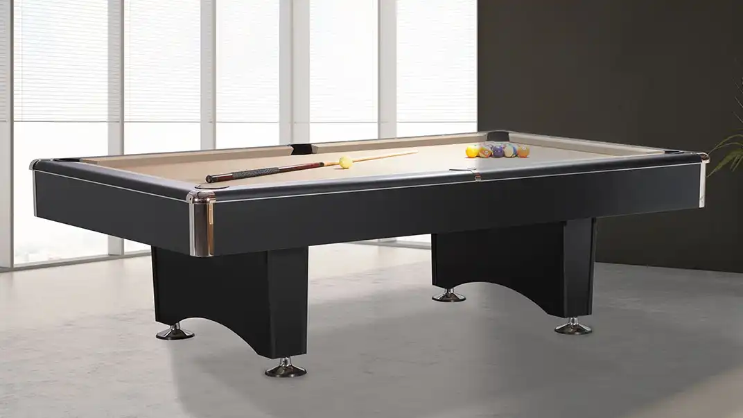 Sleek black professional pool table with tan felt, chrome corner accents, and arched pedestal legs, featuring a cue stick and billiard balls on top.