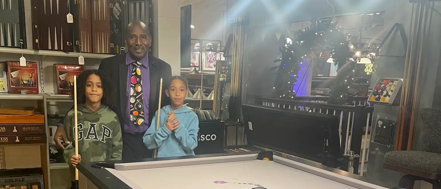Students and an instructor pose with cues during a pool school session, highlighting local youth billiards coaching and equipment.