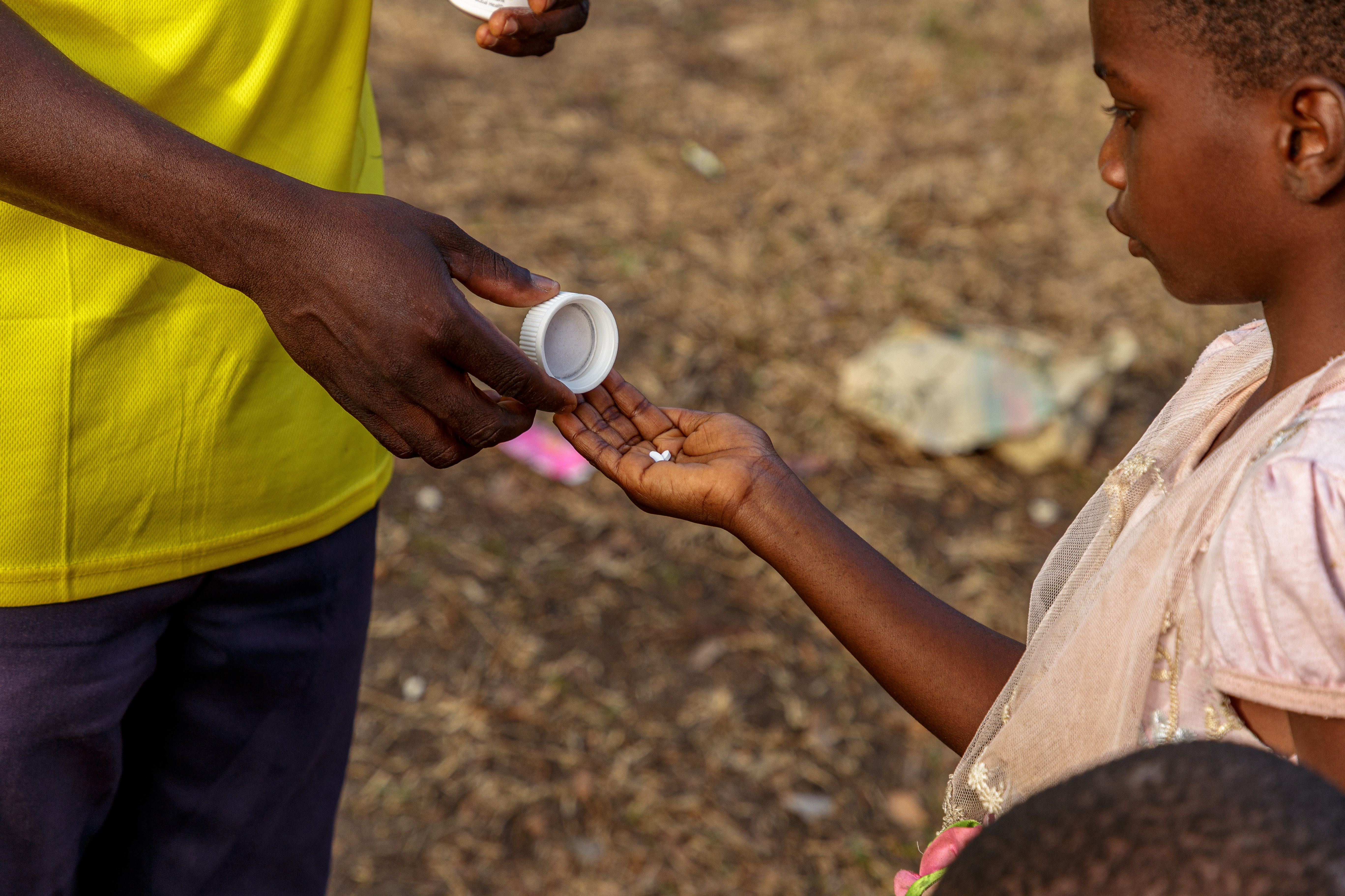 One man giving pills to another man who is the holding pills in his right hand.