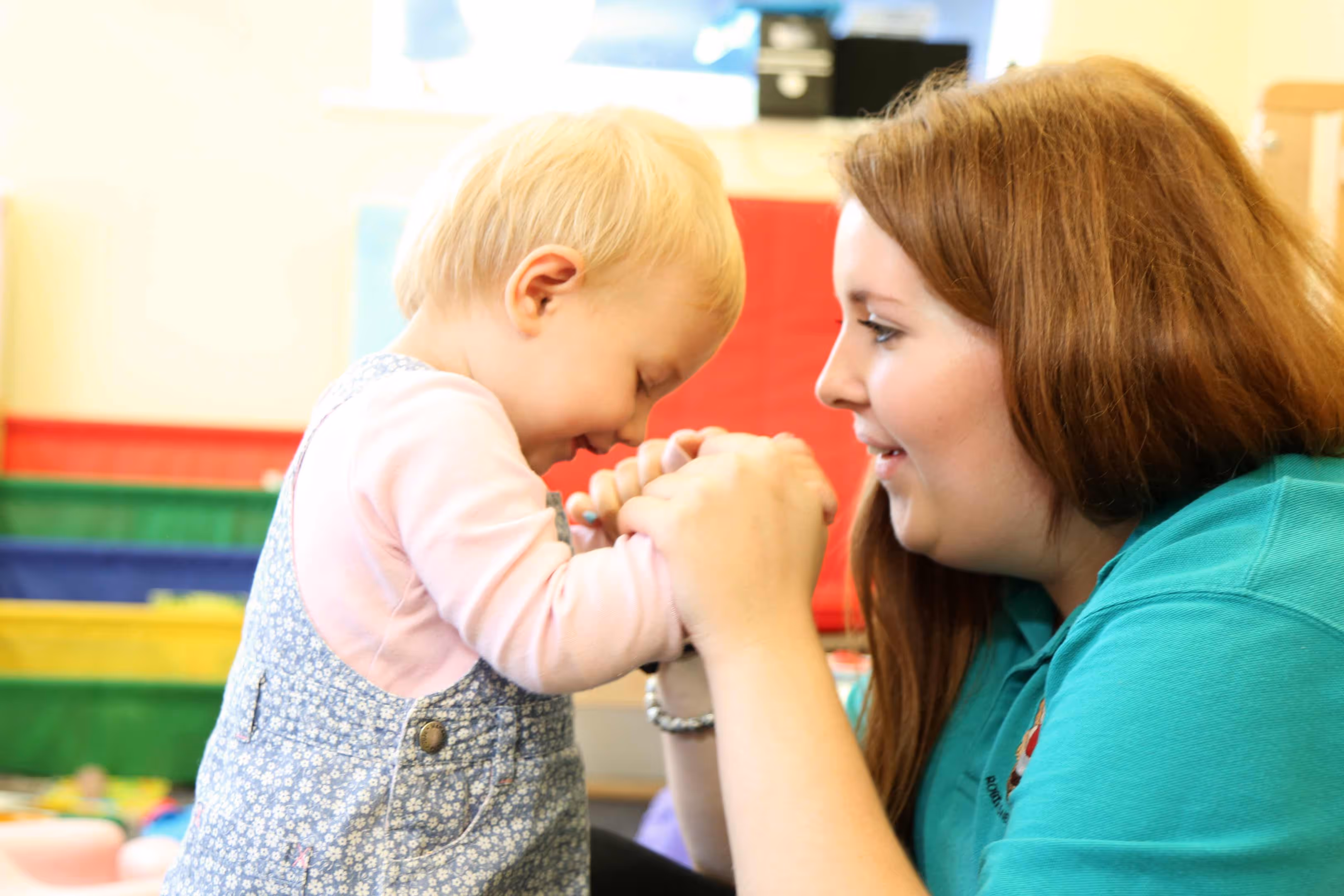 Little girl holding teachers hands smiling