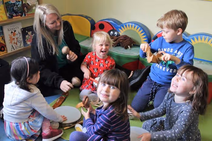 Group of children laughing together with a teacher