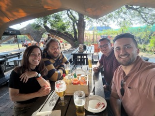 Four people enjoying food together at an outdoor restaurant.