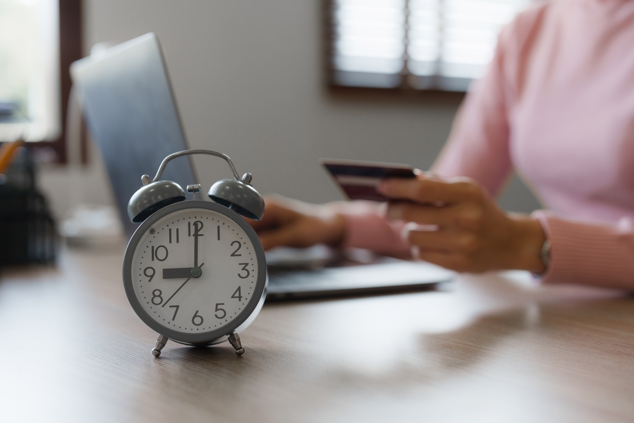 alarm clock on desk of prospect making purchase with credit card and laptop after successful sales call that demonstrated urgency