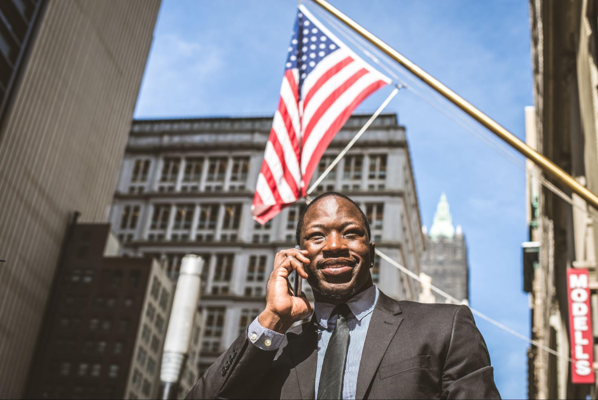 Prospect taking call from political campaign under American flag on building downtown