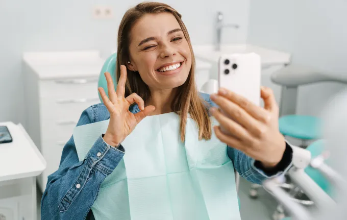 Smiling young woman in a dental chair taking a selfie, your visit to our Staten Island dental office