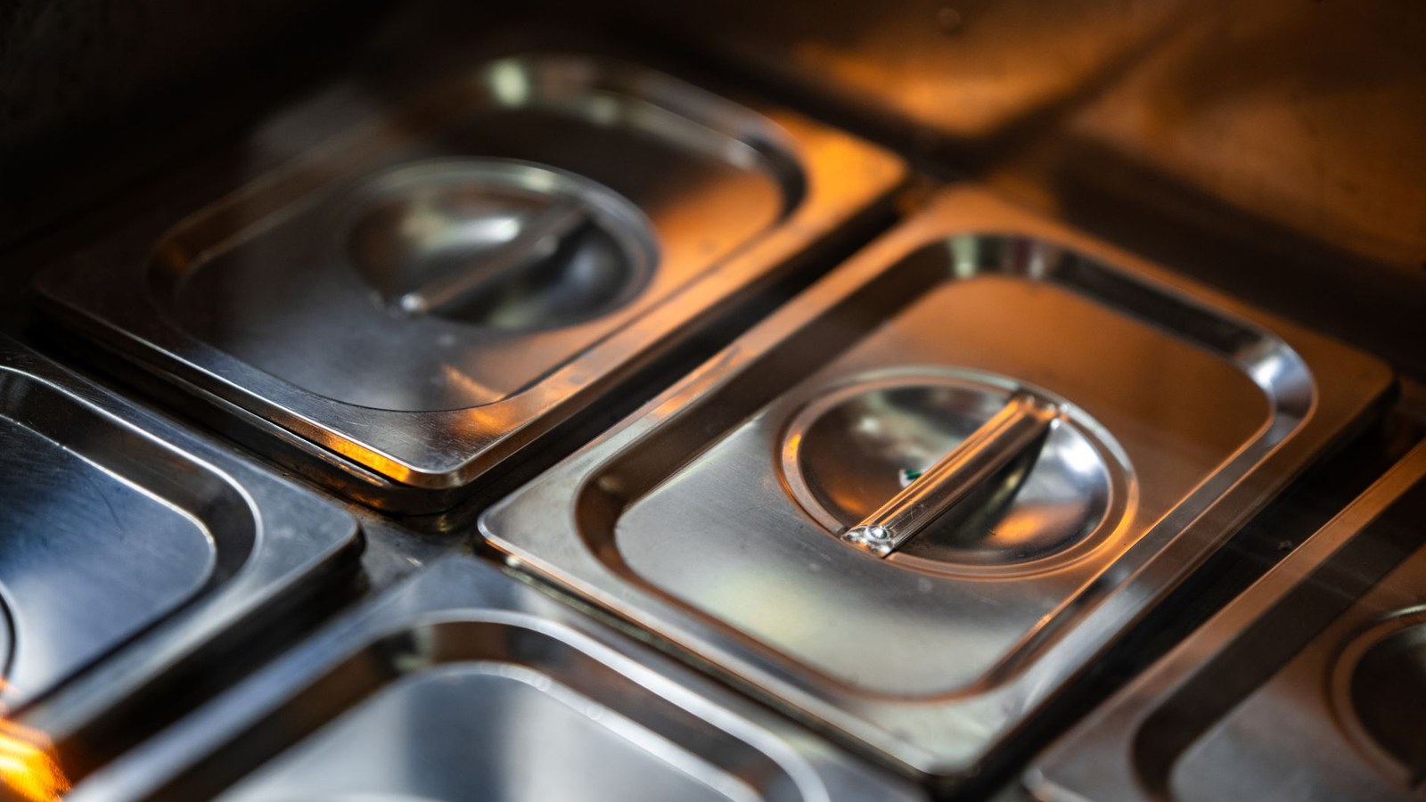 Stacks of stainless steel food containers in a professional kitchen