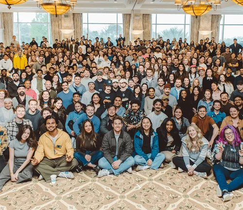 Large diverse group of people posing indoors in multiple rows, smiling and facing the camera.