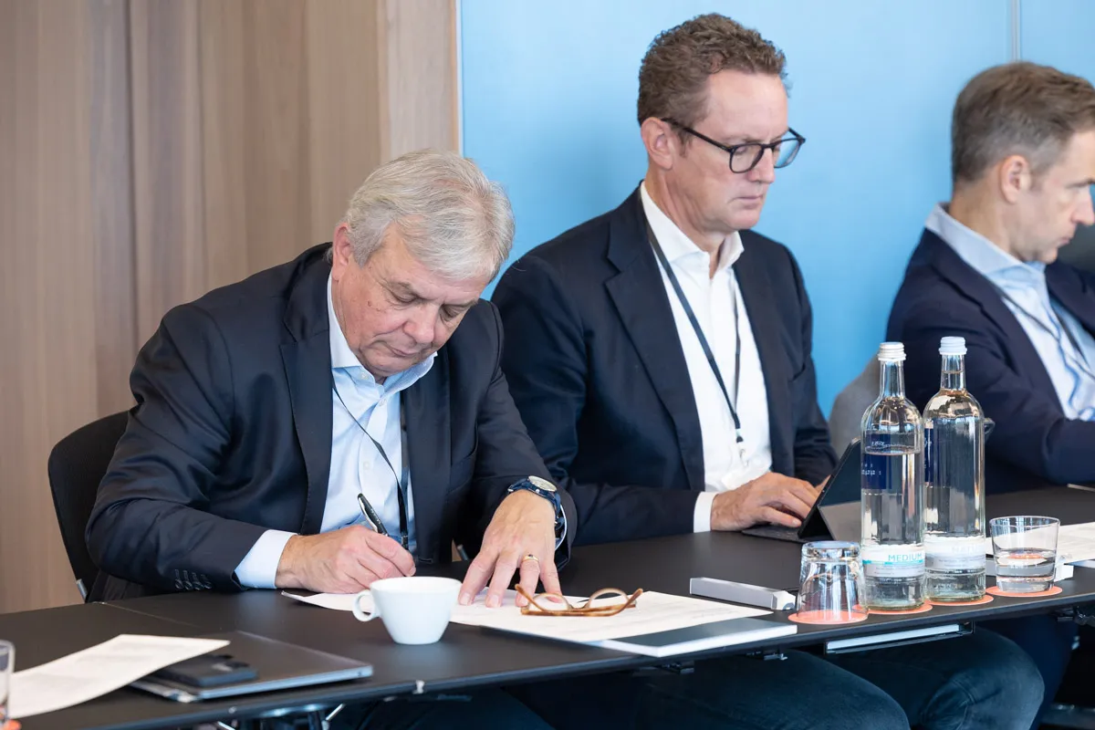2 Männer im Anzug machen sich Meeting Notizen