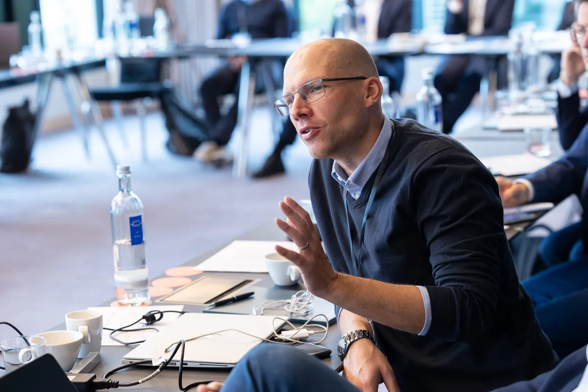 Mann diskutiert mit anderen an einem Tisch