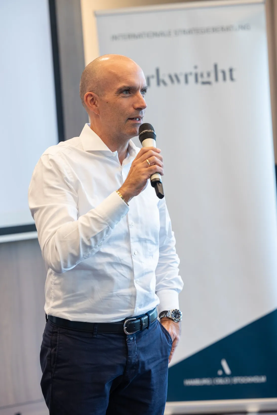 Mann in weißem Hemd spricht in ein Mikrofon
