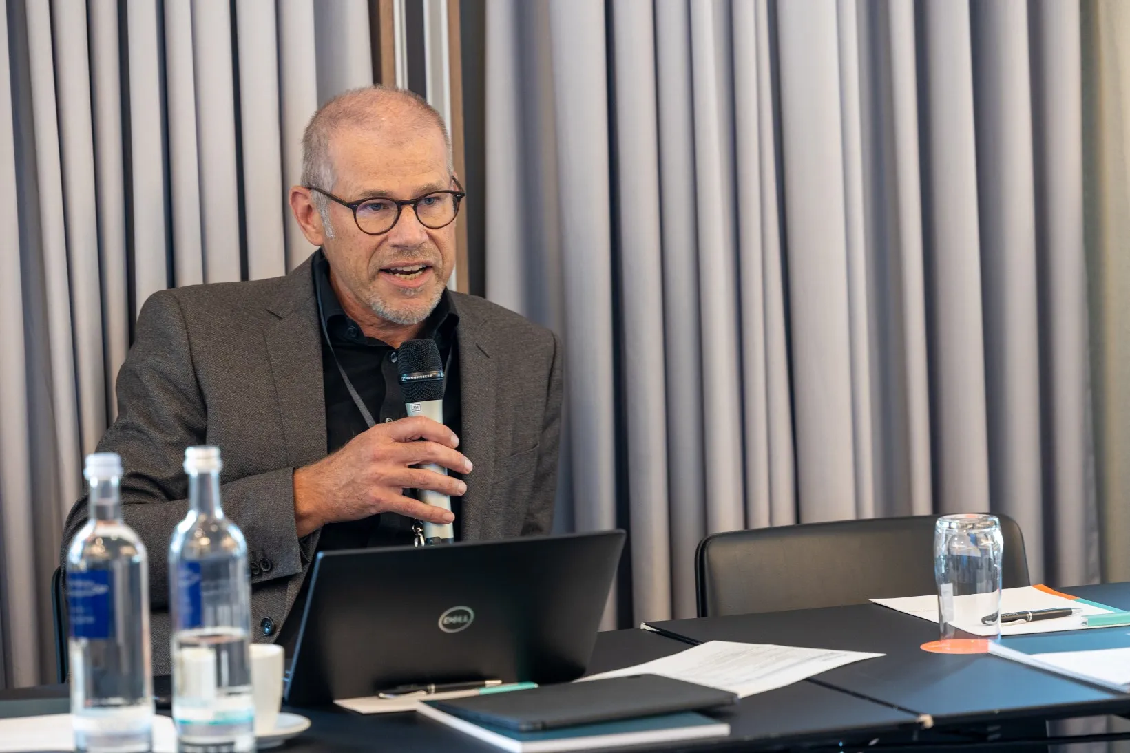 Mann in grauem Sakko hält Mikrofon