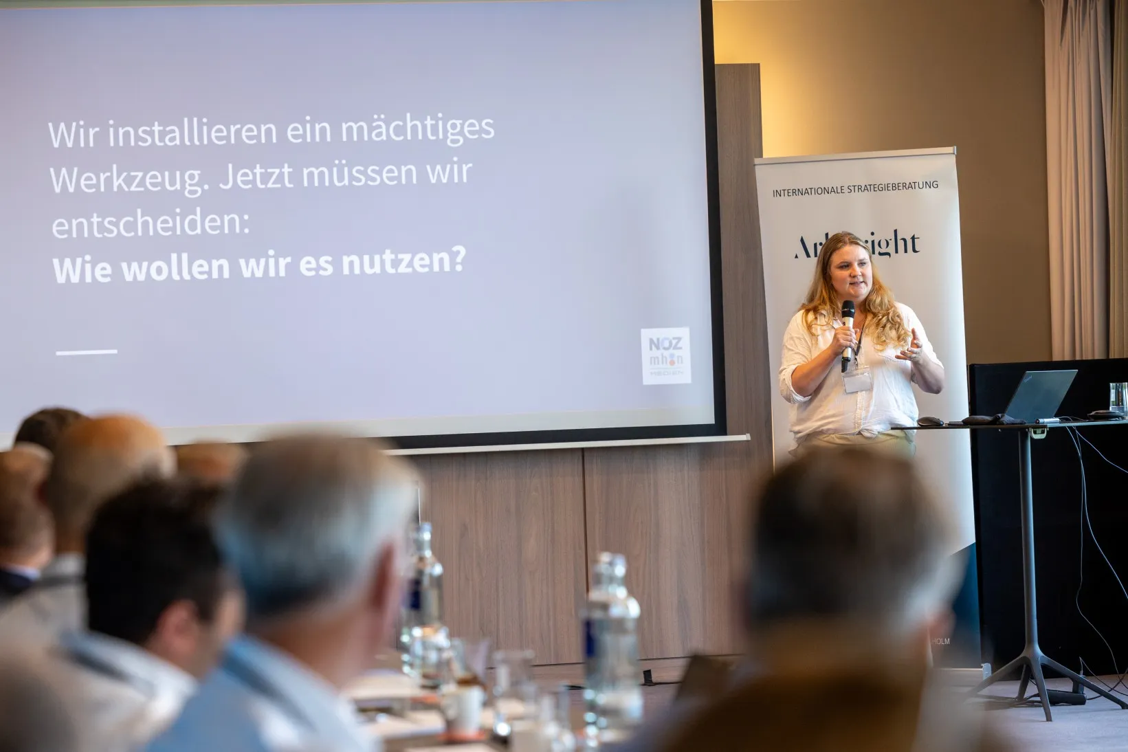 Frau in weißem Hemd spricht in ein Mikrofon, Fernaufnahme