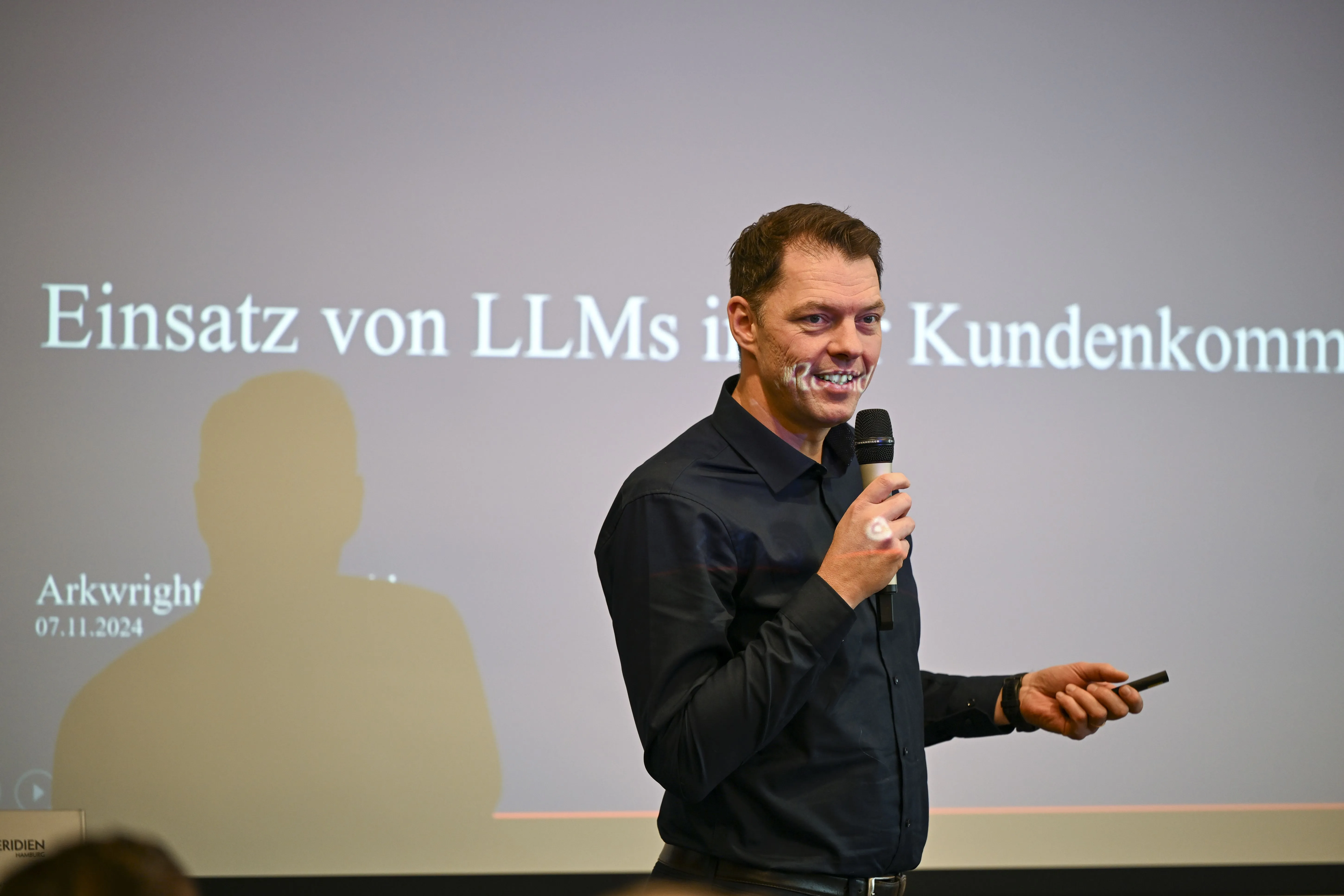Mann in schwarzem Hemd spricht in ein Mikrofon