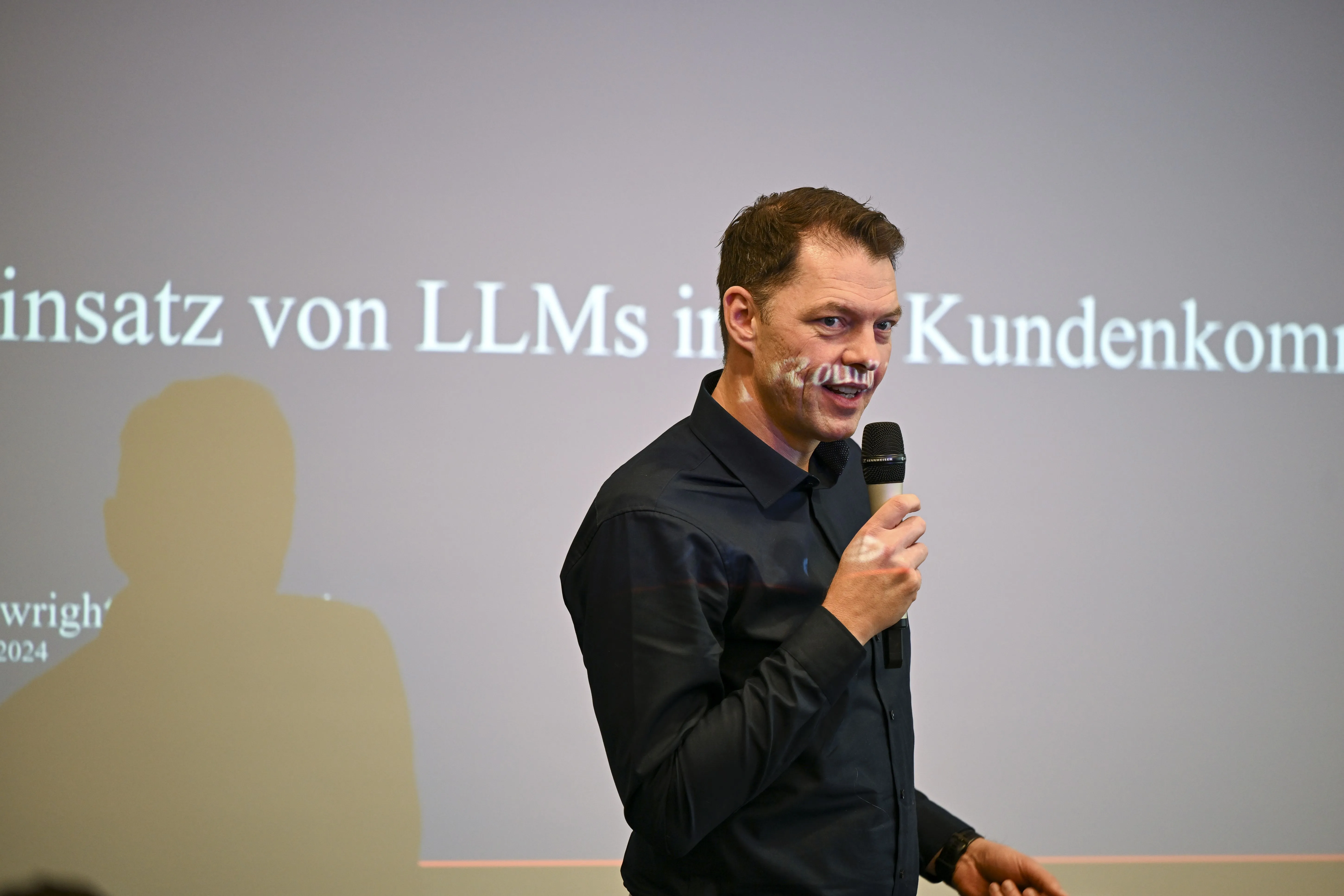 Mann in schwarzem Hemd spricht in ein Mikrofon