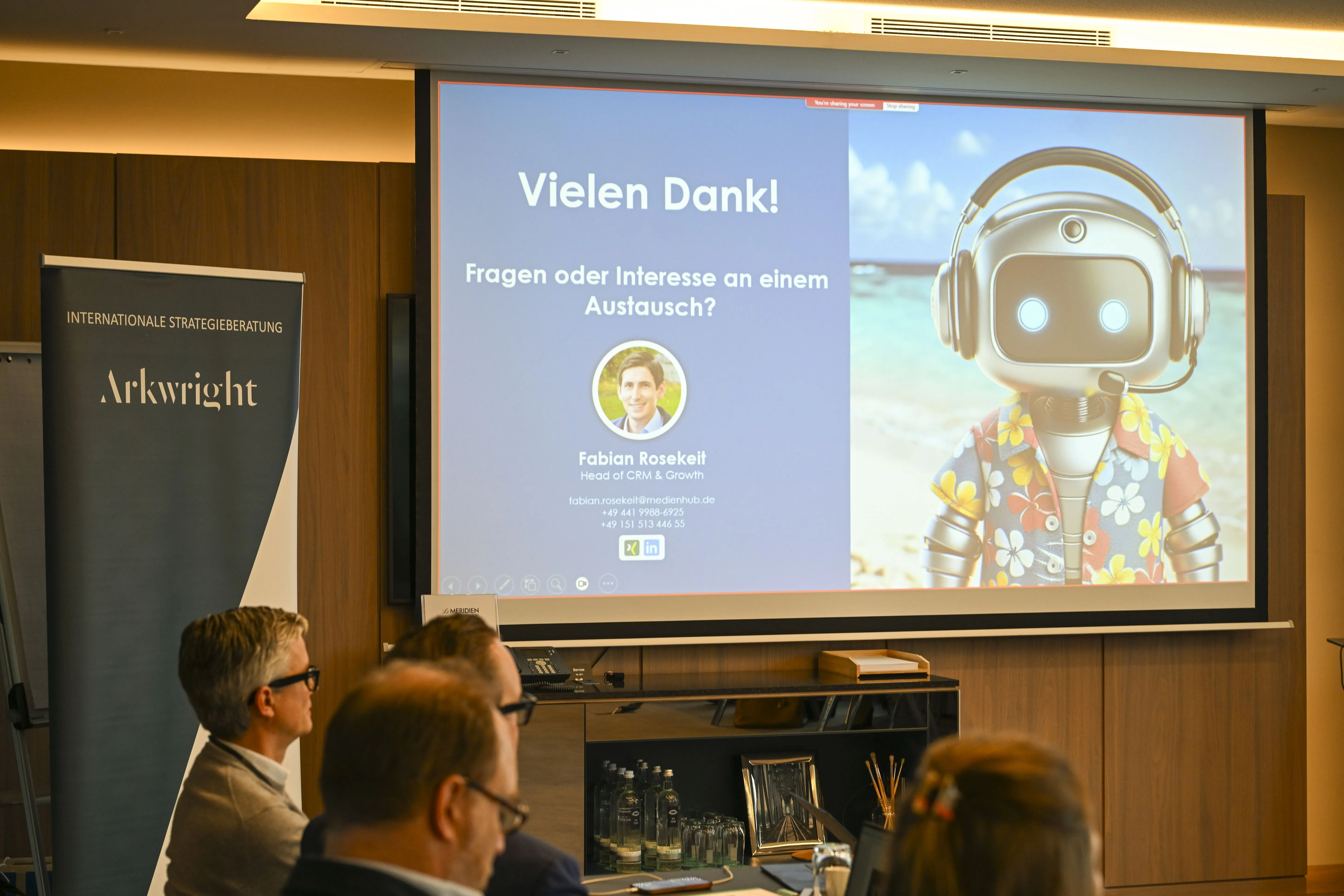 Ansicht eines Meetingraumes, Fokus ist auf den Vortragsfolien der Präsentation